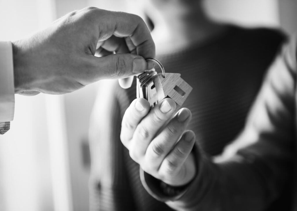 Manos de dos personas entregándose la llave de una vivienda