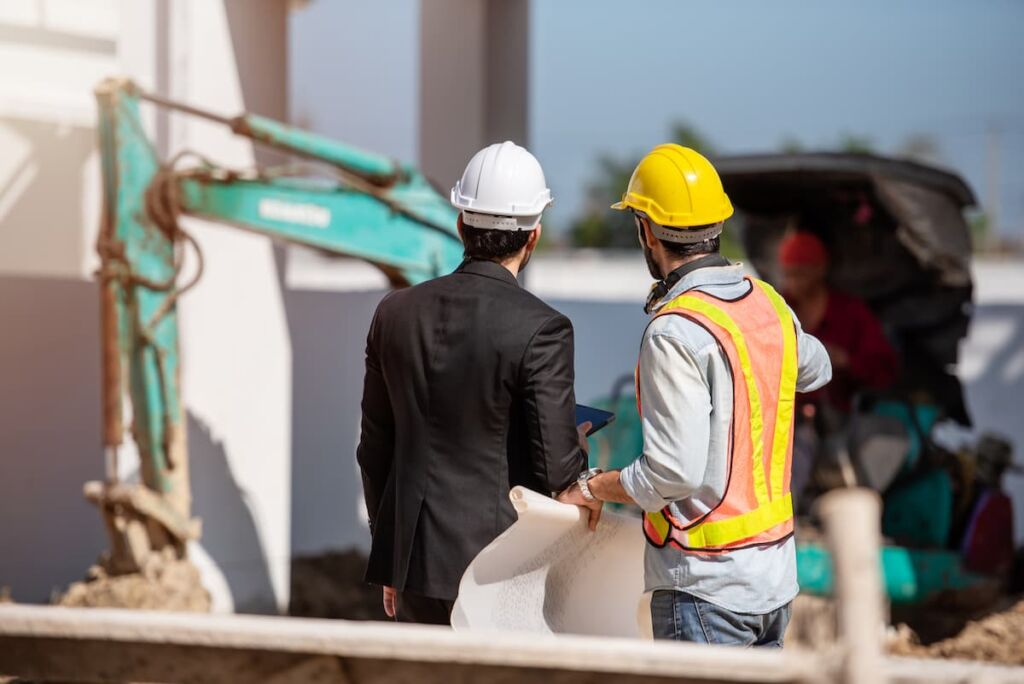 Obrero e ingeniero de una construcción trabajando juntos mirando hacia la construcción