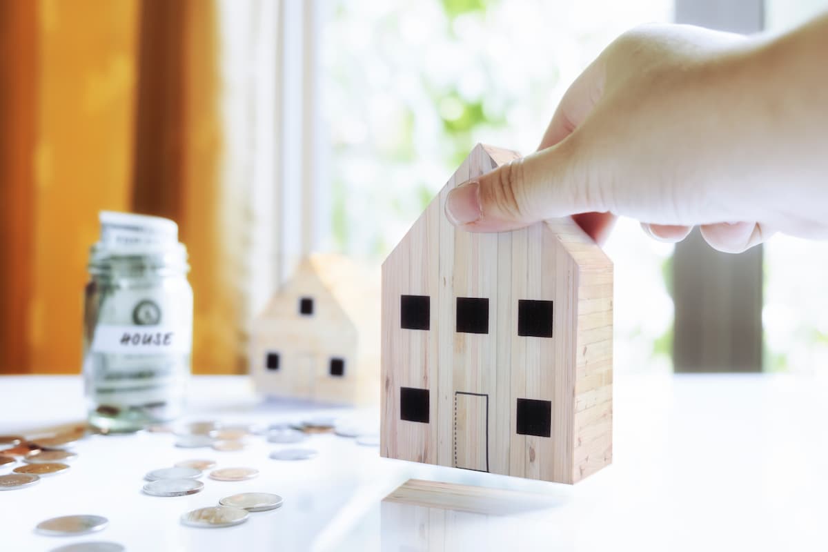 monedas y casa de madera simulando la inversión en una hipoteca y la lección entre los tipos de hipotecas más adecuados